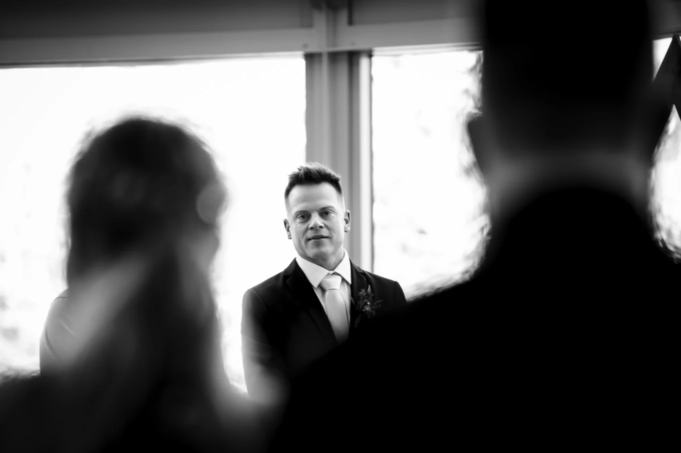 First look of the groom while the bride walking down the aisle in black and white.