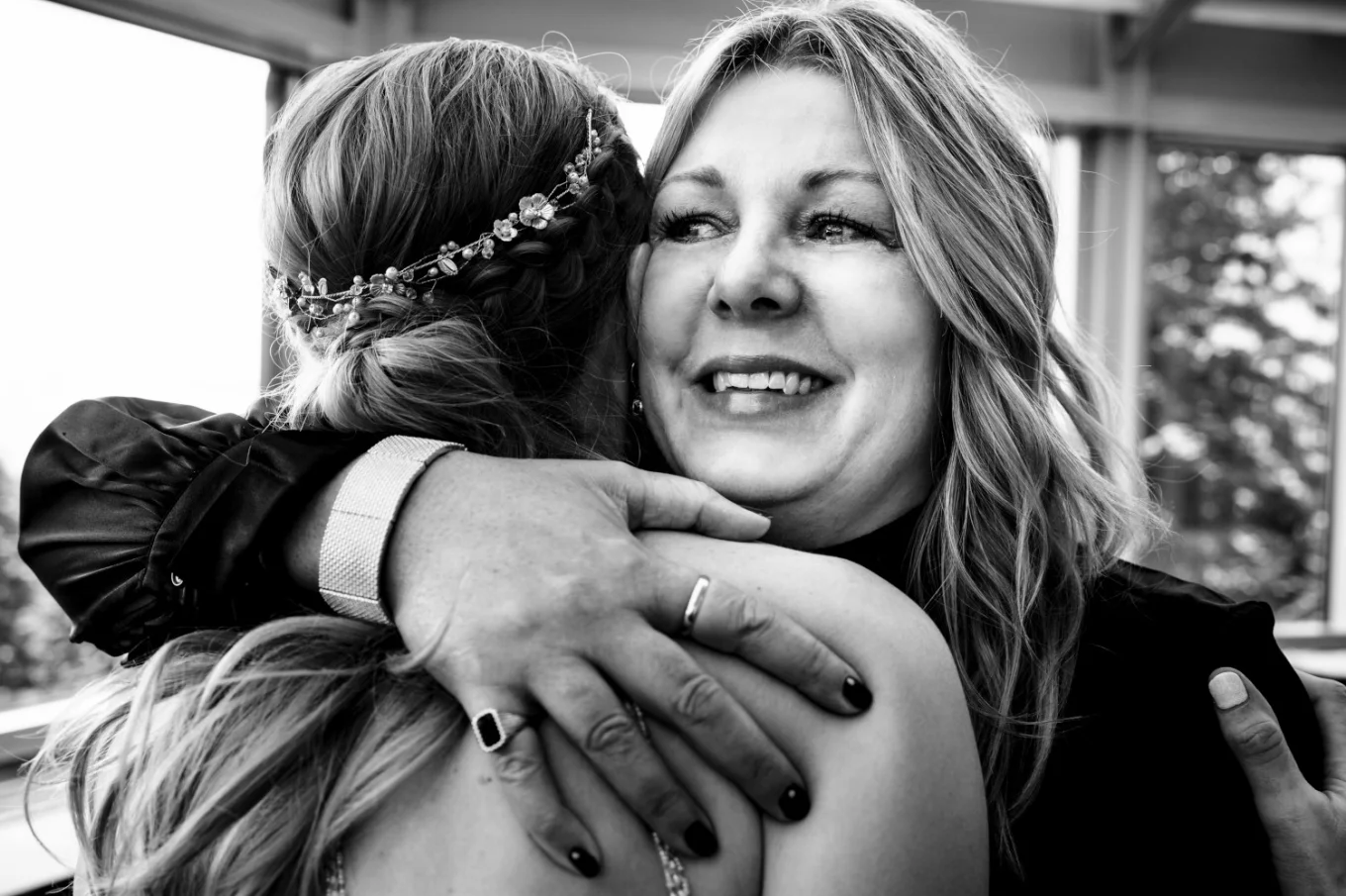 Sister of the groom hugs the bride with tears in her eyes.