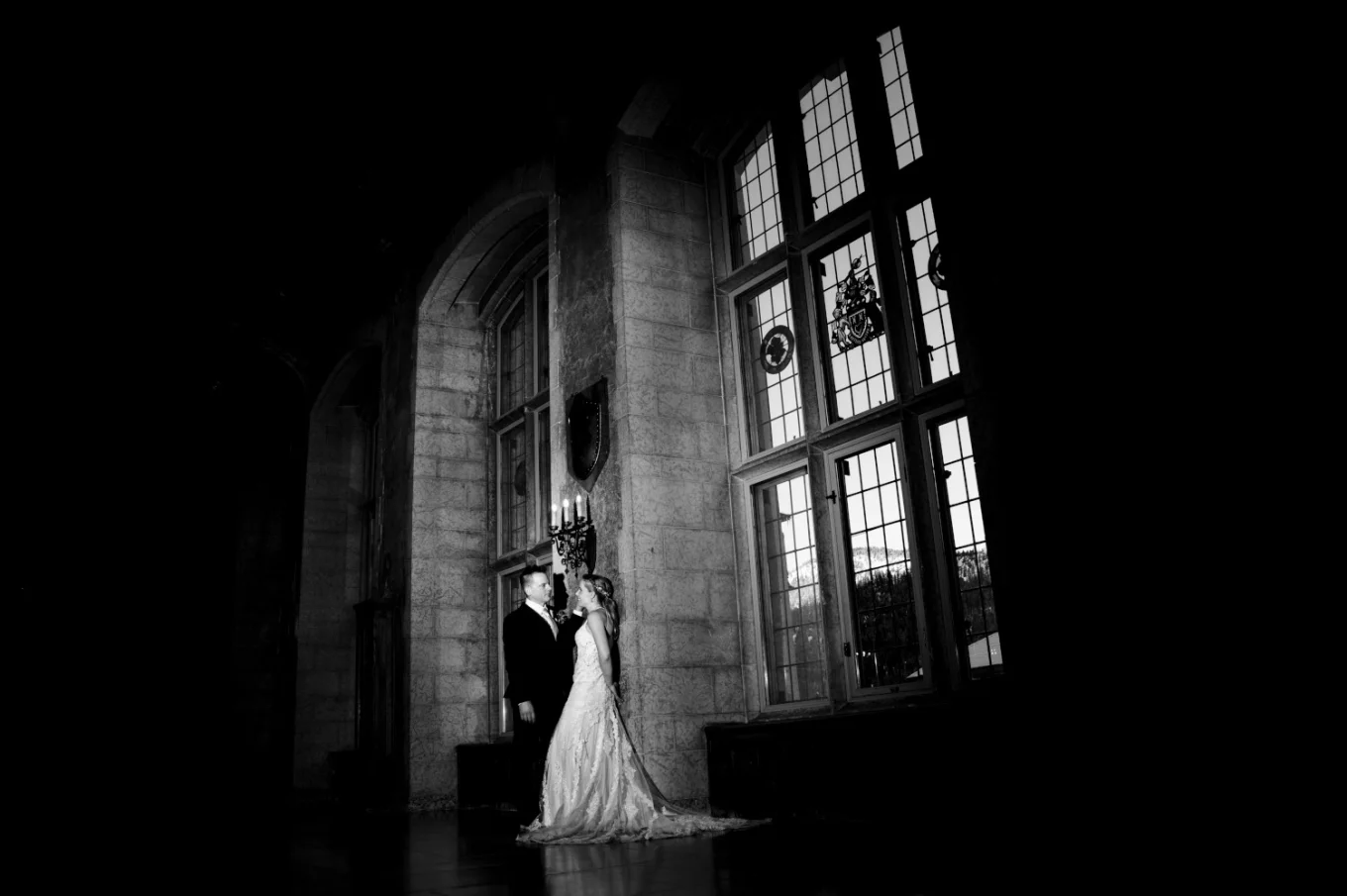 Newlyweds lean on the wall next to the unique widows at Fairmont Banff Springs.
