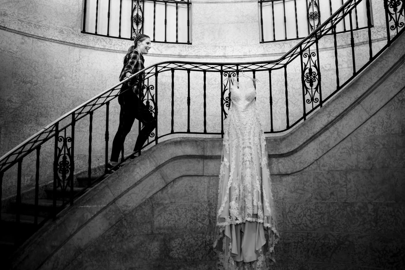 The bride walking up the stairs at Fairmont Banff Hotel. Her wedding dress hanging on the rails.