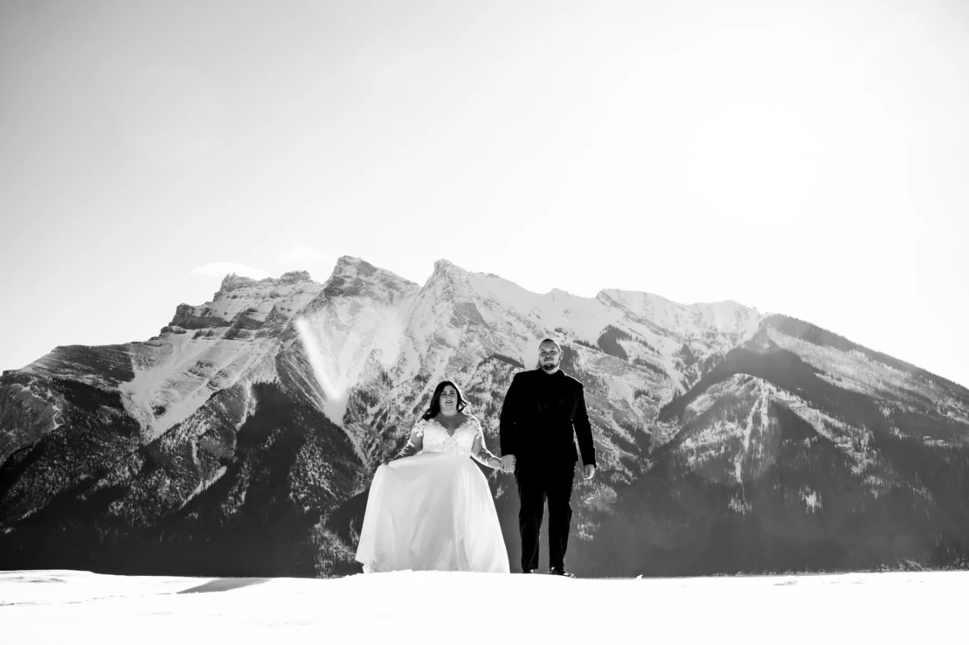Black and white Banff Wedding Photography of the newlyweds walking in the mountains and holding their hands.