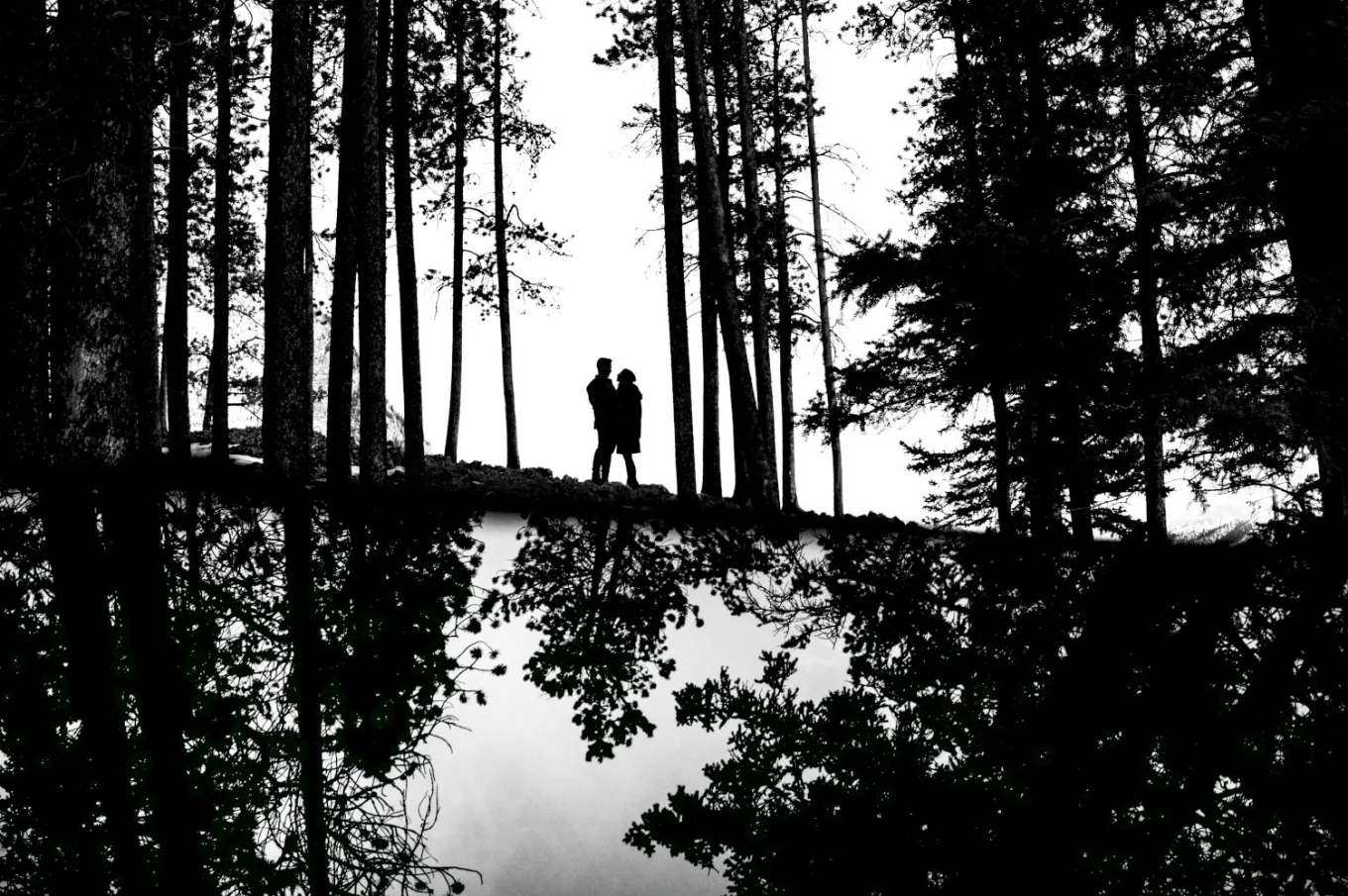 Engaged couple in Banff standing in a hug, surrounded by the forest.