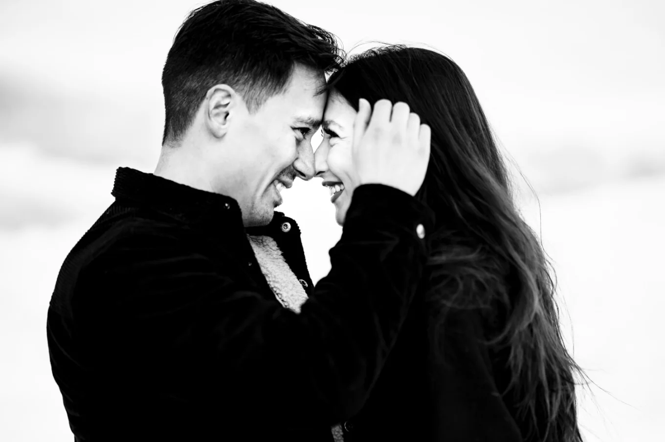 Romantic photograph of the man and his fiancee looking at each other while he brushes her hair.