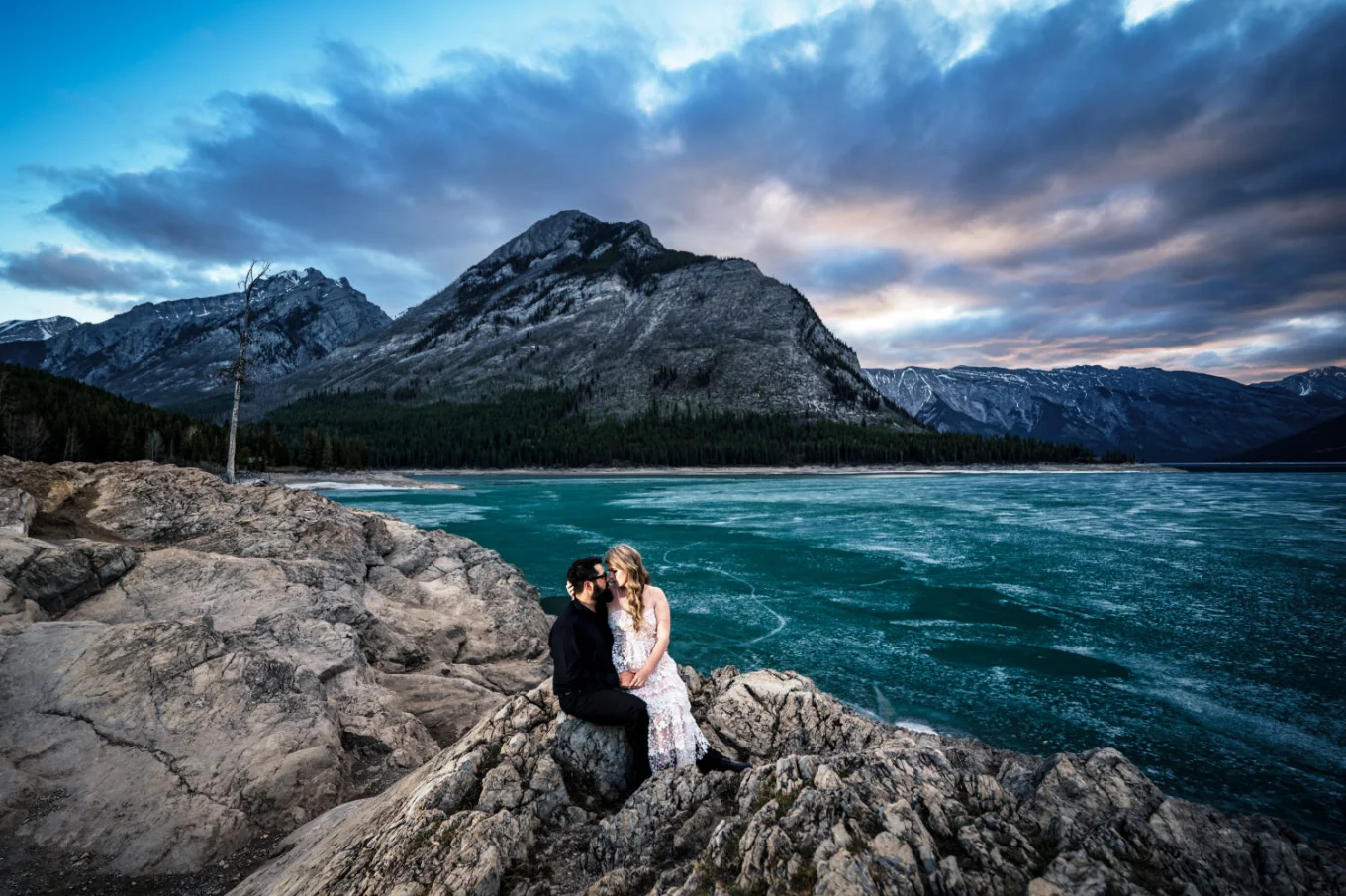 Woman sits at her fiance's lab by the frozen Minnewanka Lake in Banff National Park.