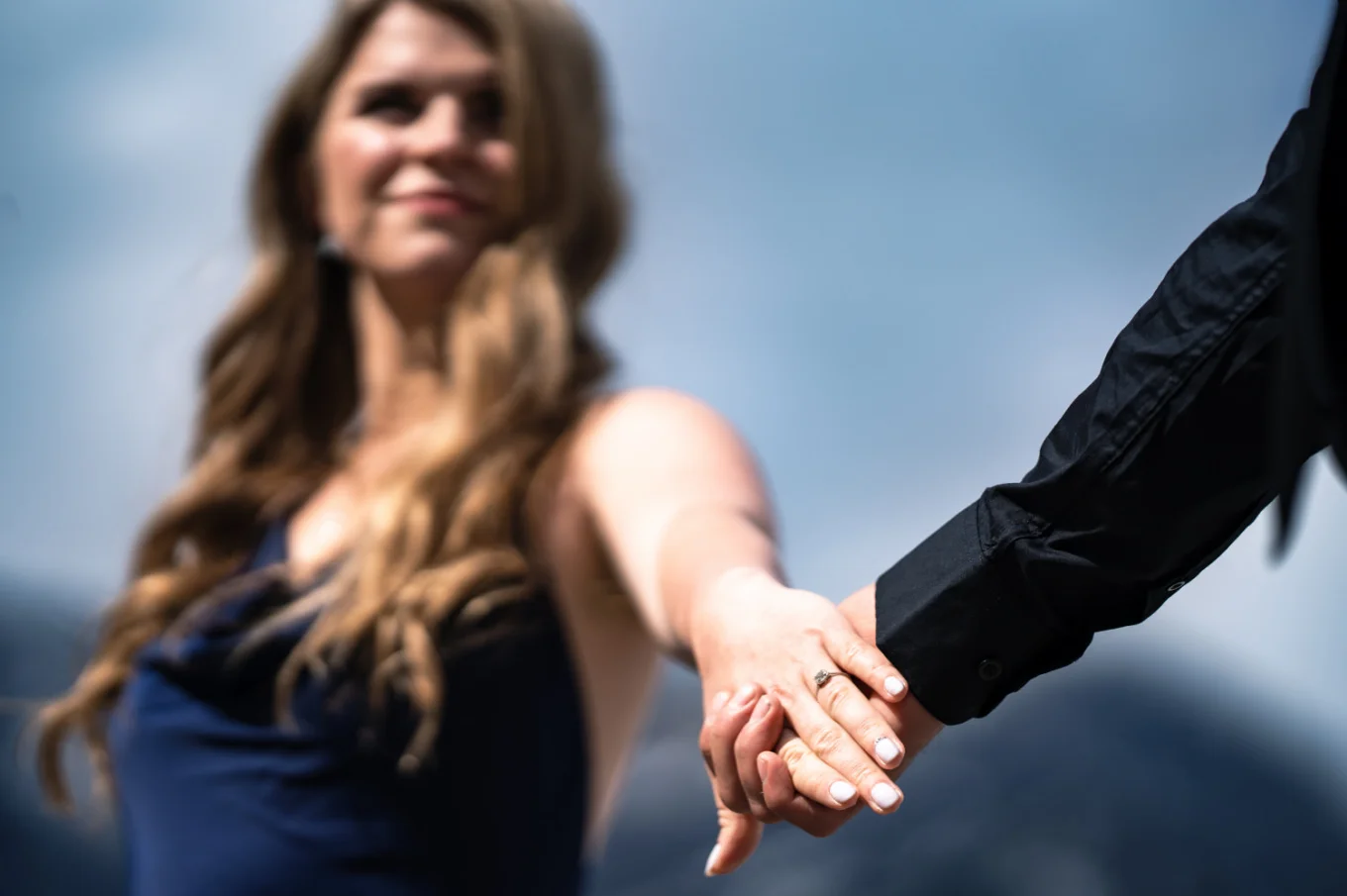 Photograph of the couple holding their hands with the focus on the giant engagement ring.