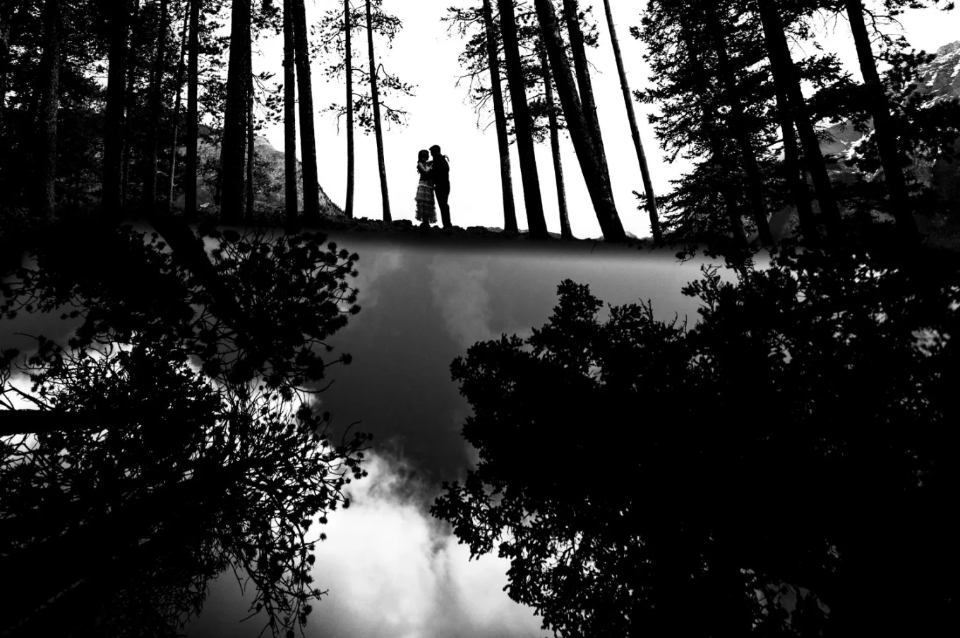 Creative photograph in black and white of the couple in the reflected forest.