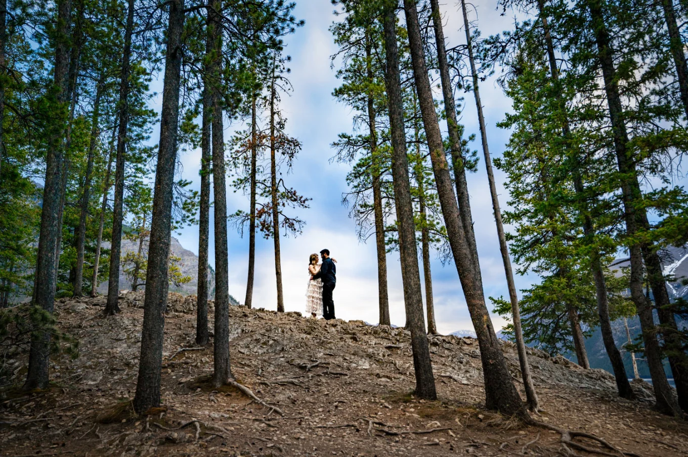 Couple in a hug in the middle of the Banff's forest.