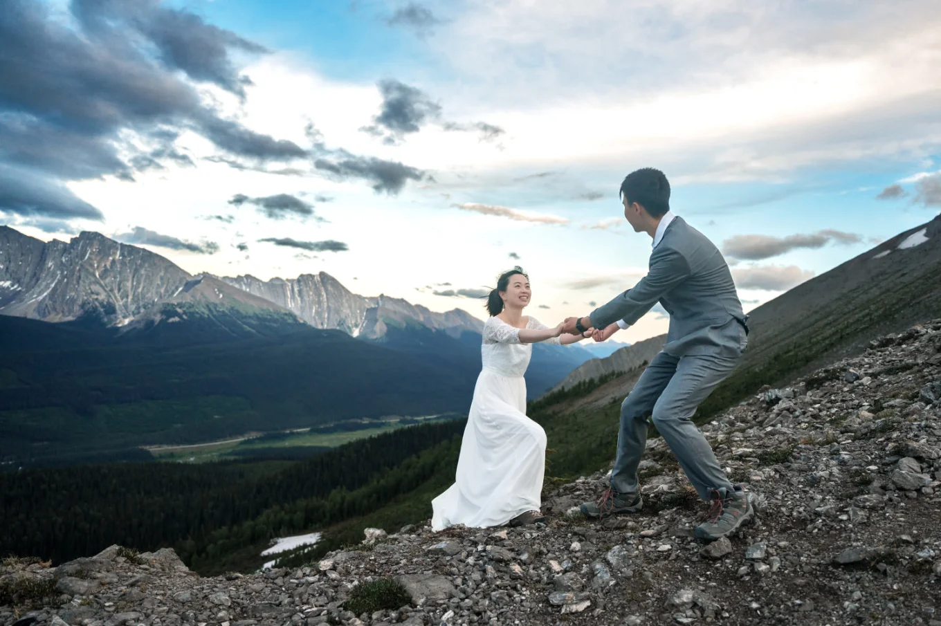 Groom helps the bride climb the mountain.