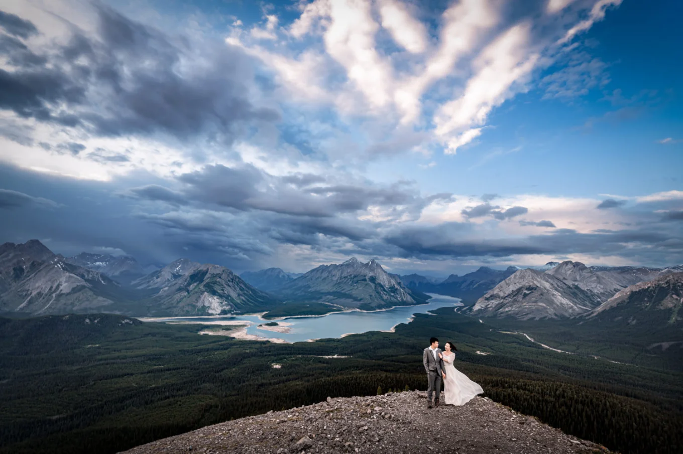 Stunning photograph taken by Banff Wedding Photographer if the newlyweds standing in a hug at the edge on the mountain.