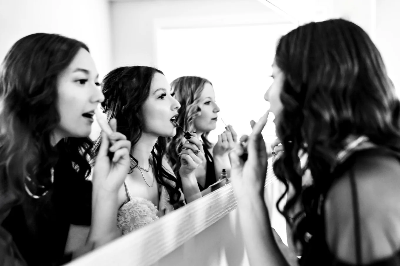 bride and bridesmaids fixing their make up in front of the big mirror