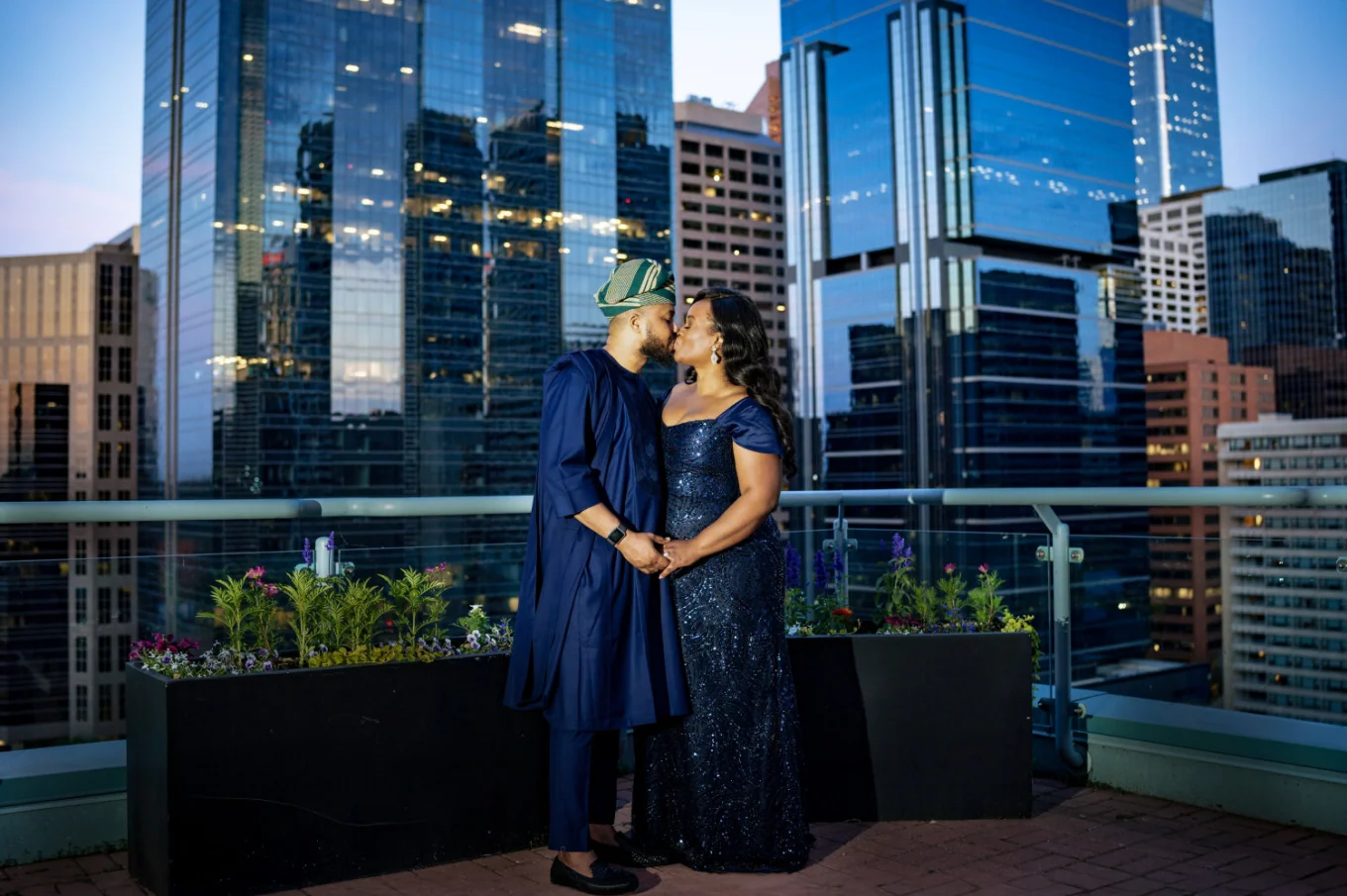 Newlyweds dresser in a traditional Nigerian attire share a kiss on the balcony. On the background the view on the city of Calgary.