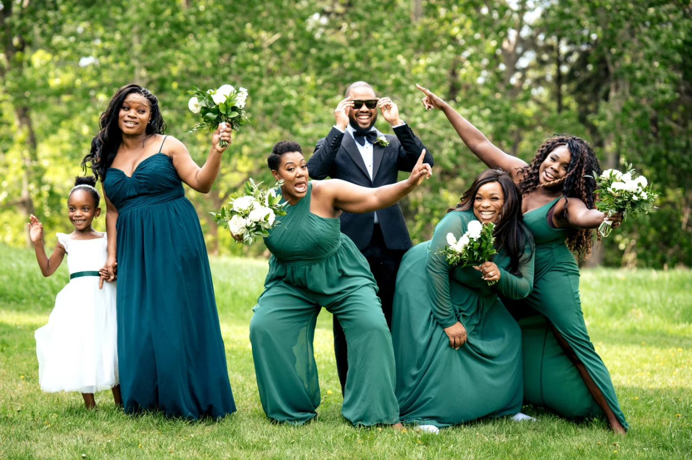 Bridal party lift the hands up while the groom fixes his glasses. Funny bridal party photography taken by Calgary Wedding Photographer.