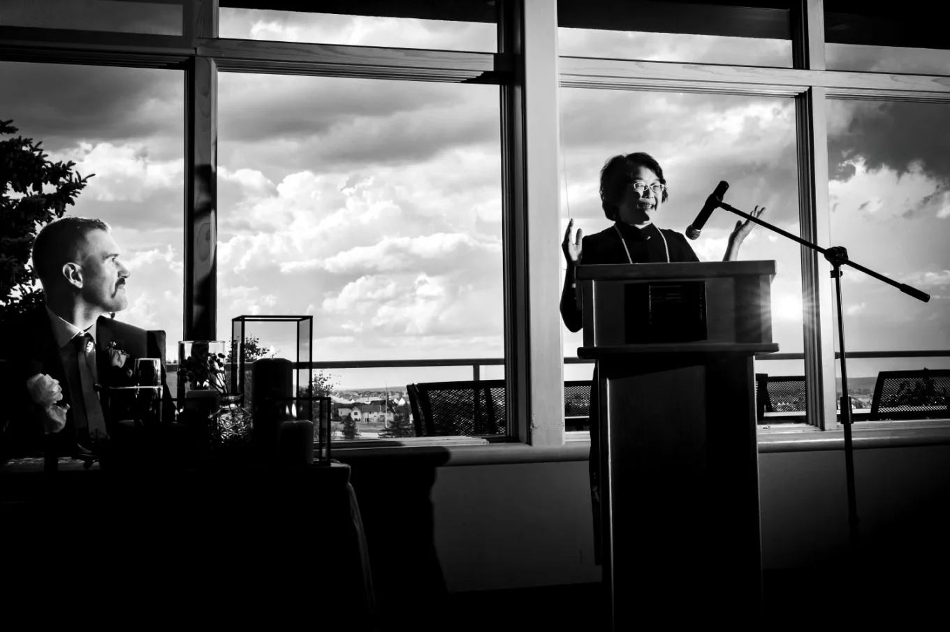 mother of the bride gives a speech during Wedding Reception. behind the window heavy clouds.