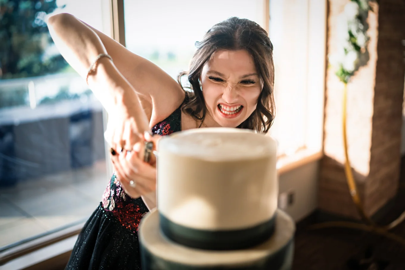 The bride tries to cut the wedding cake, she makes a funny faces.