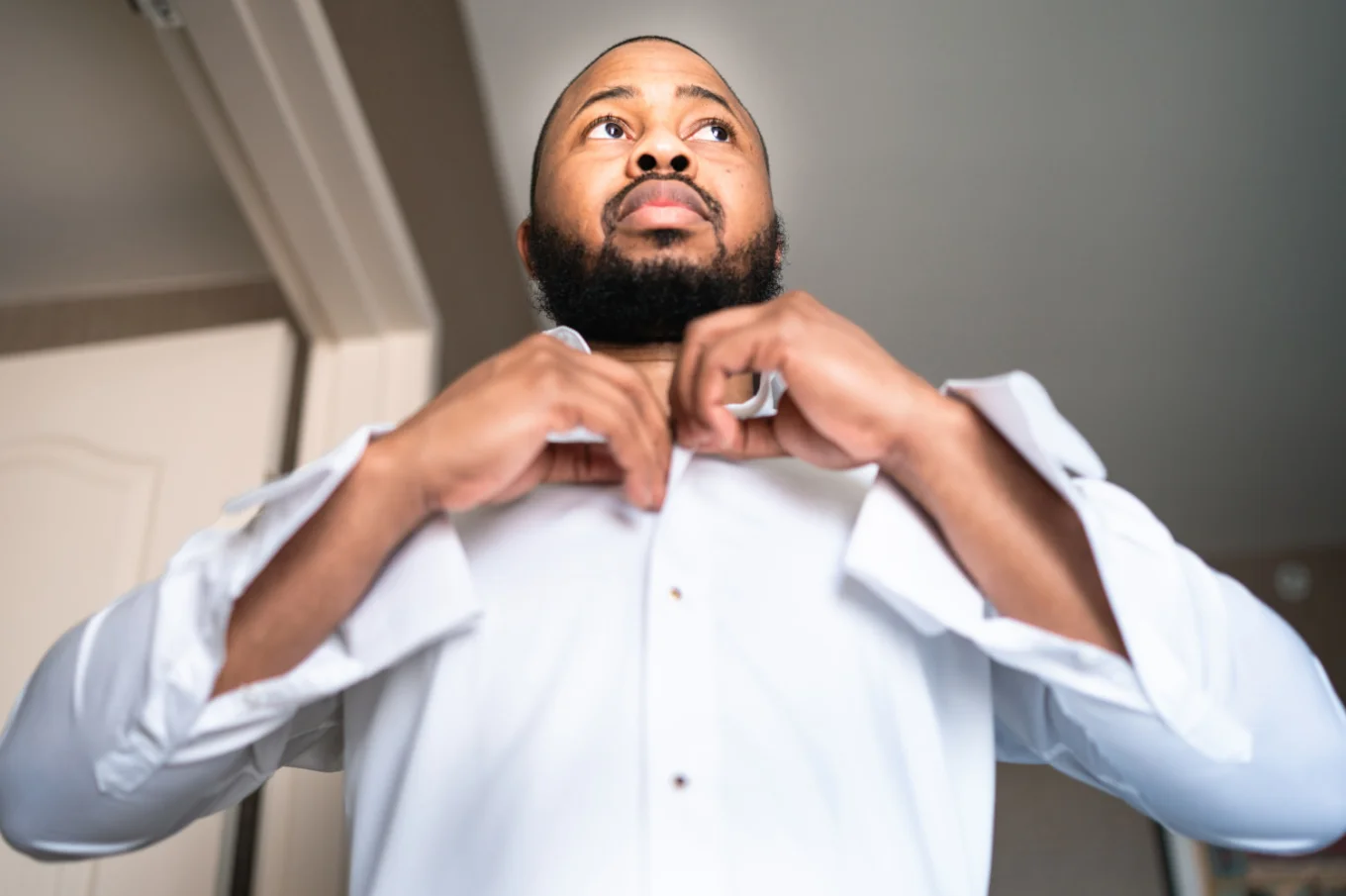 The groom buttons up his shirt before wedding ceremony in Calgary.