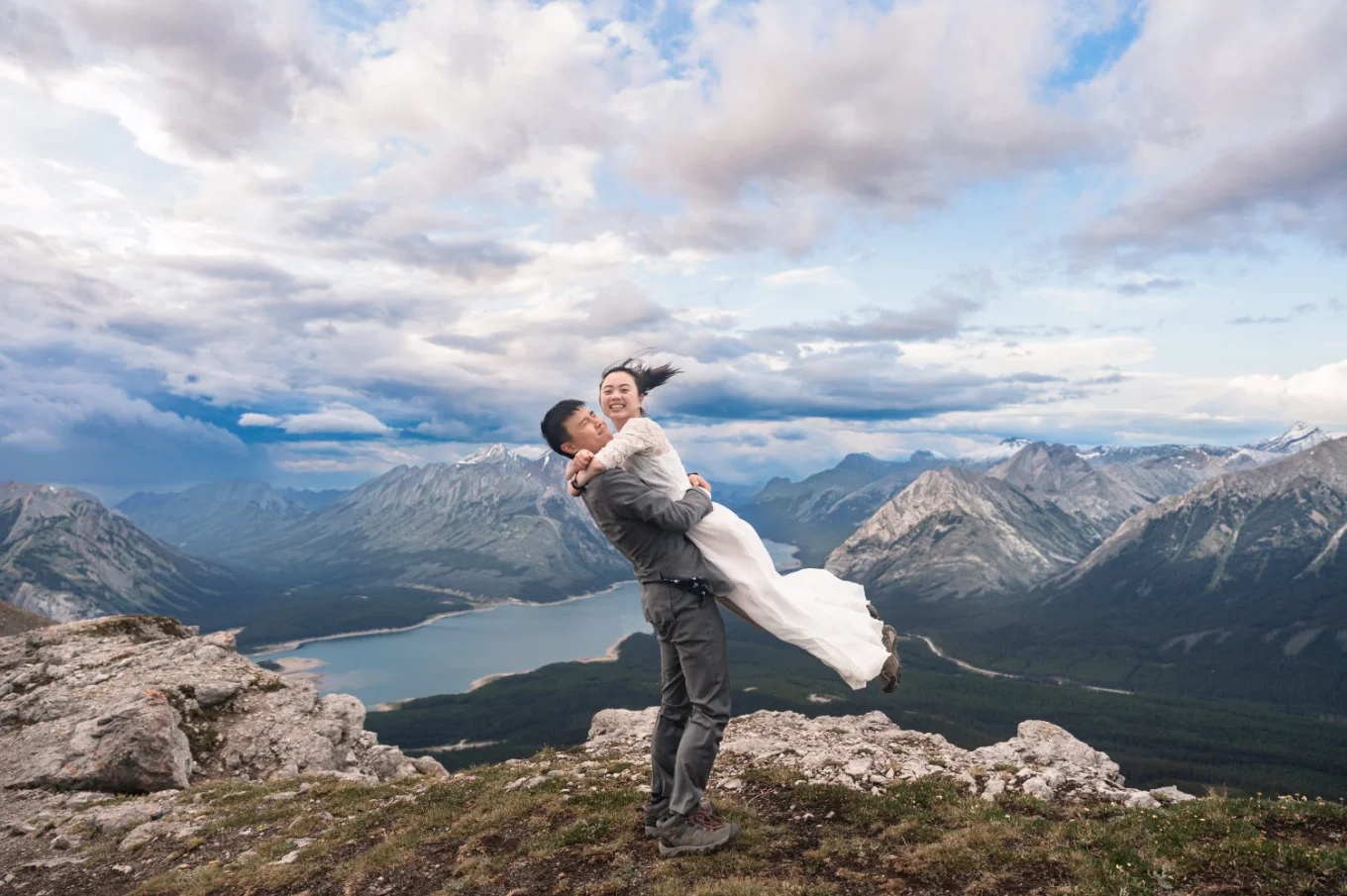 The groom lift the bride at the end of their hiking adventure with Banff Wedding Photographers. They are both happy.