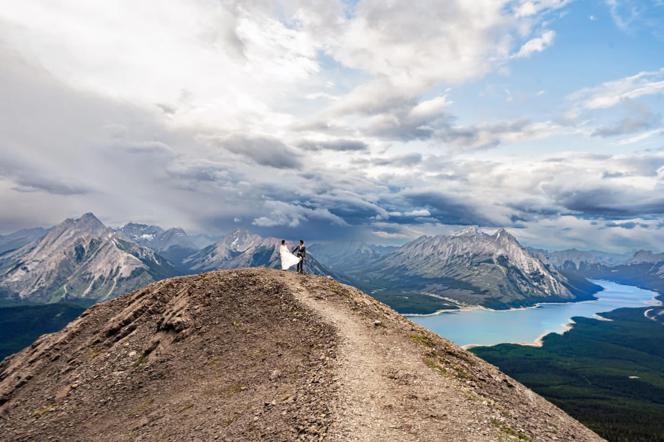 Newlyweds walk on the ridge of the mountain with the panoramic view on the Canadian Rockies a the lake.