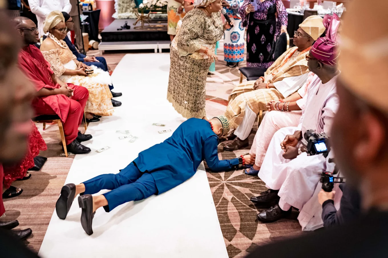 Groom laying on the floor and touches his parents feet during Nigerian ritual on the wedding day.