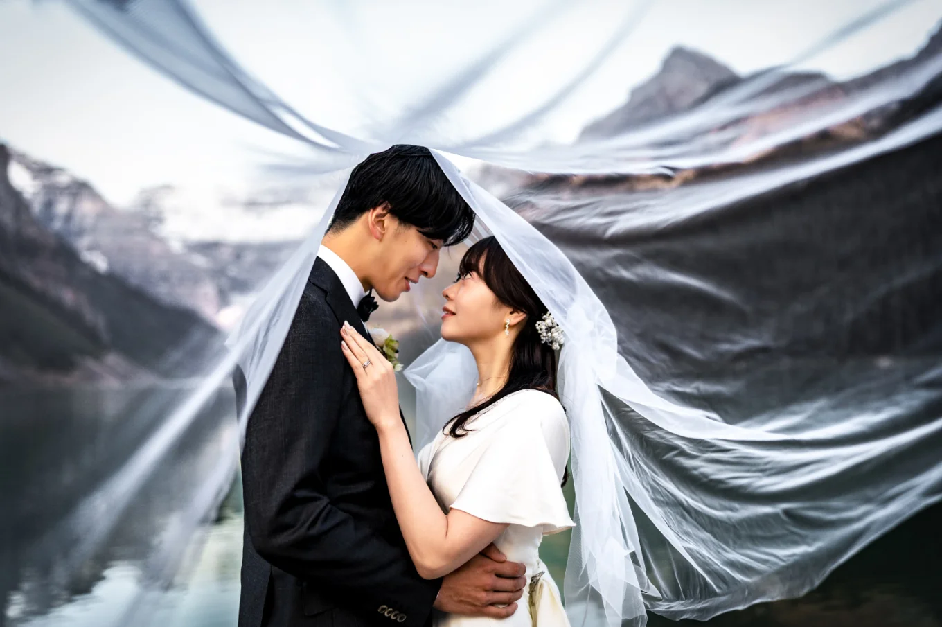 Bride and groom look at each other under the veil.