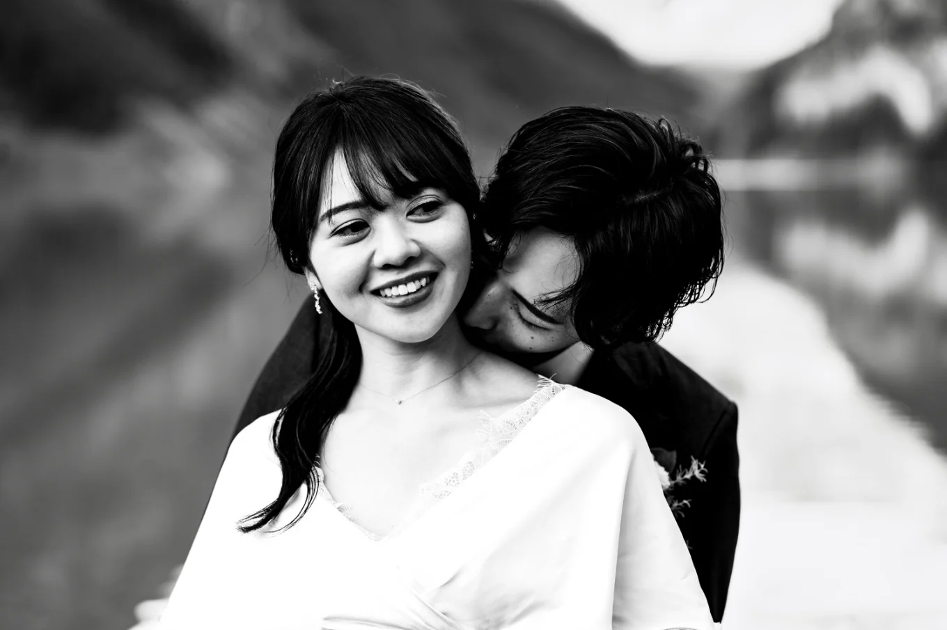 Groom kisses his wife's neck.