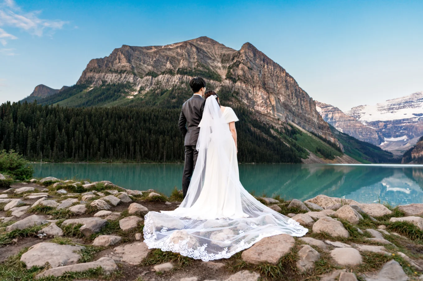 Bride and groom from behind looking at the turquoise Lake Louise.