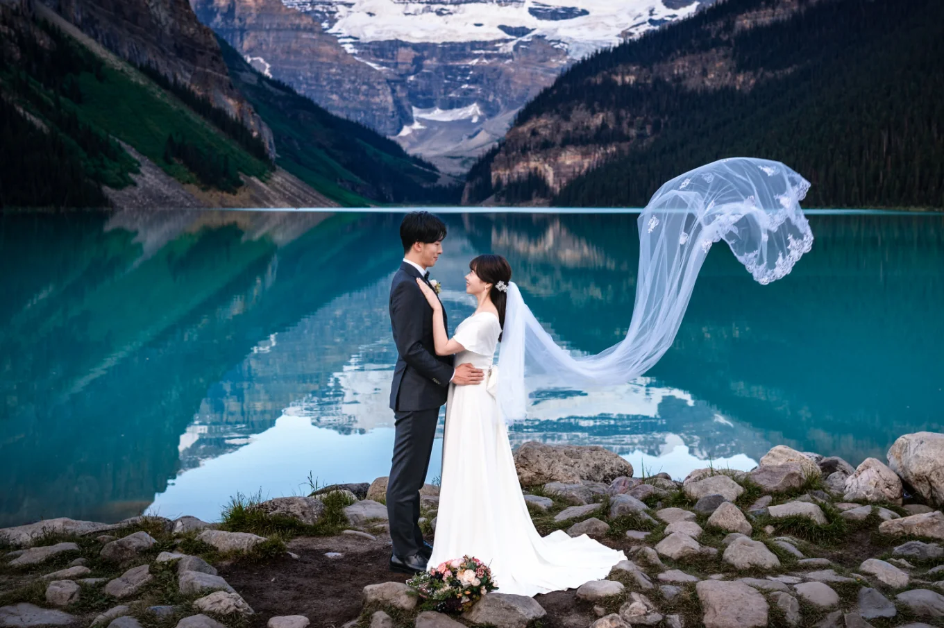 Bride and groom look at look other while the wing blow the bride's veil.