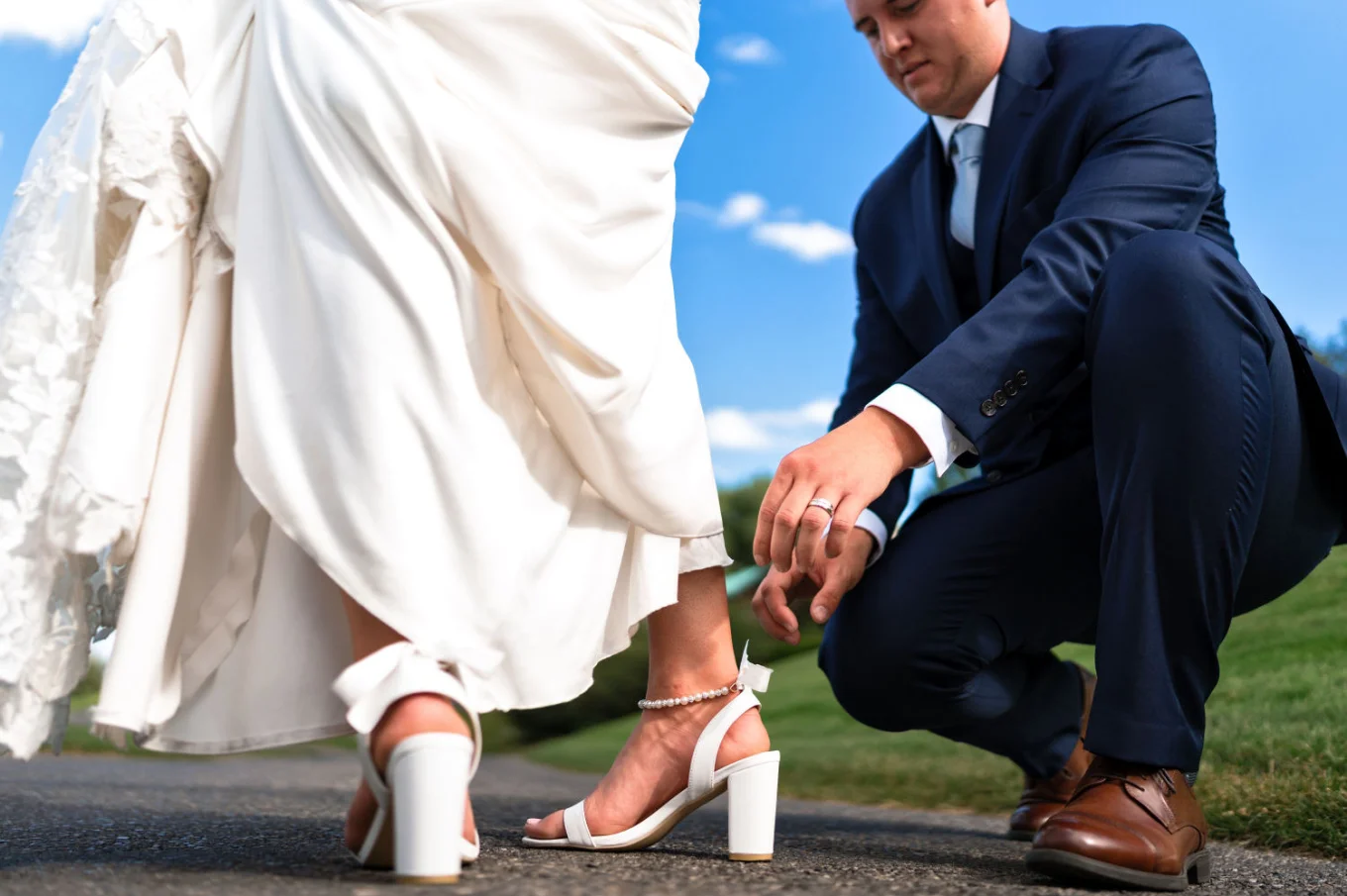 The groom fixes the bride's shoe.