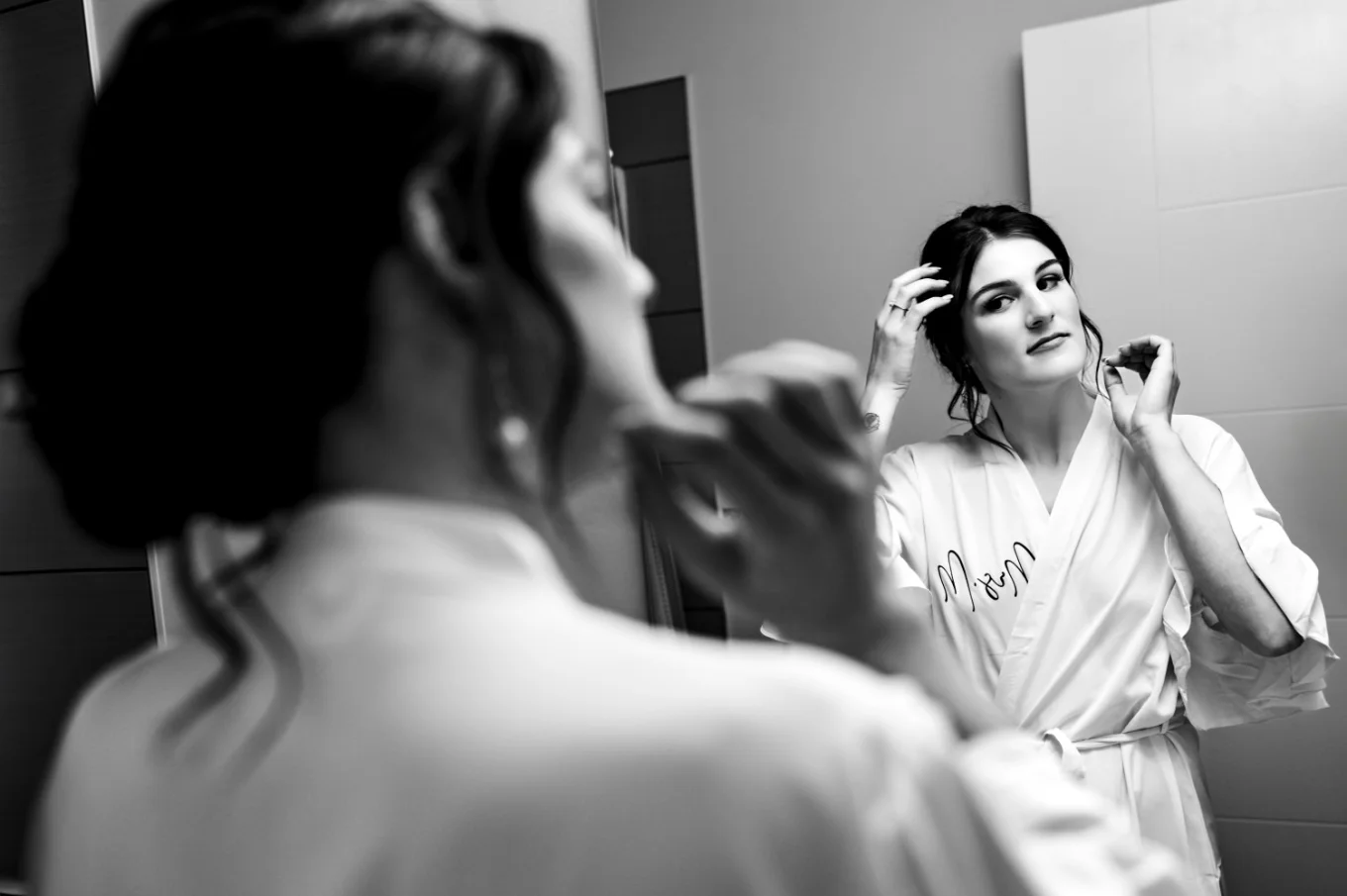 the bride looks at the mirror and fixes her hair.