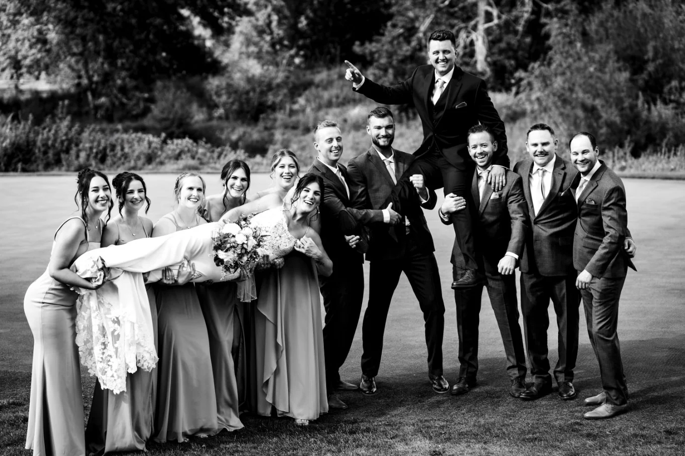 Funny photography of the bridal party lifting up the bride and groom.