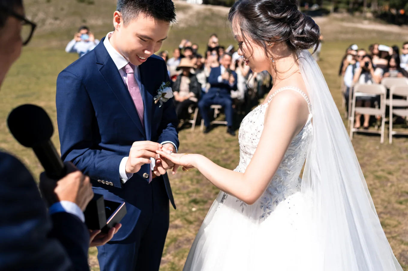 the groom puts the wedding ring on the bride's finger while all the banff wedding quests watching
