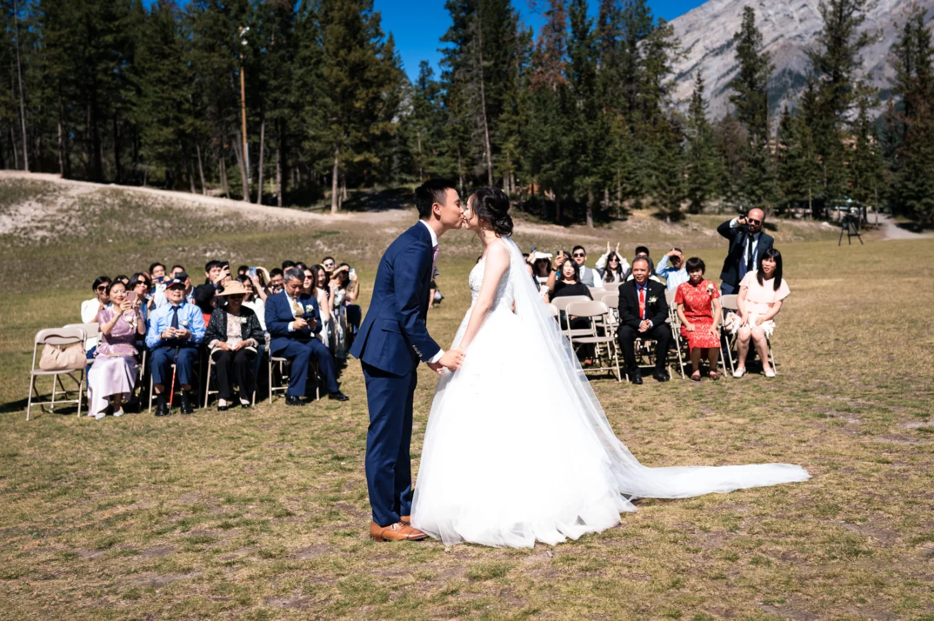 first kiss on the newlyweds in Banff. Guests on the chairs watching them.