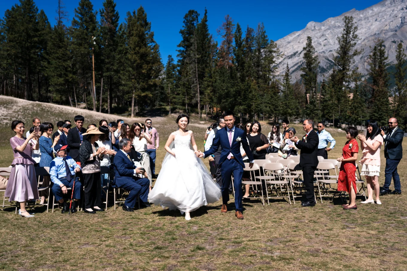 newlyweds run back on the aisle while all banff quests clapping their hands