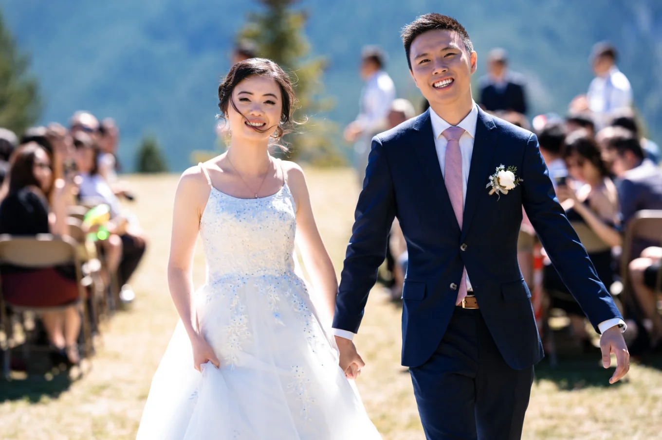 newlyweds walk out the aisle at the Banff Wedding Ceremony. They both smile and hold hands.