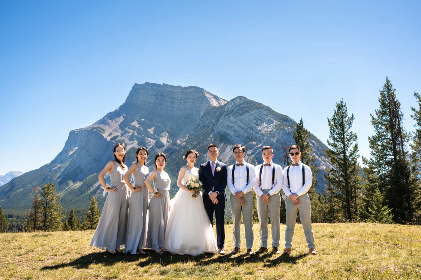 Wedding Party Banff Photograph while they look at the camera. Behind them stunning Rocky Mountains.