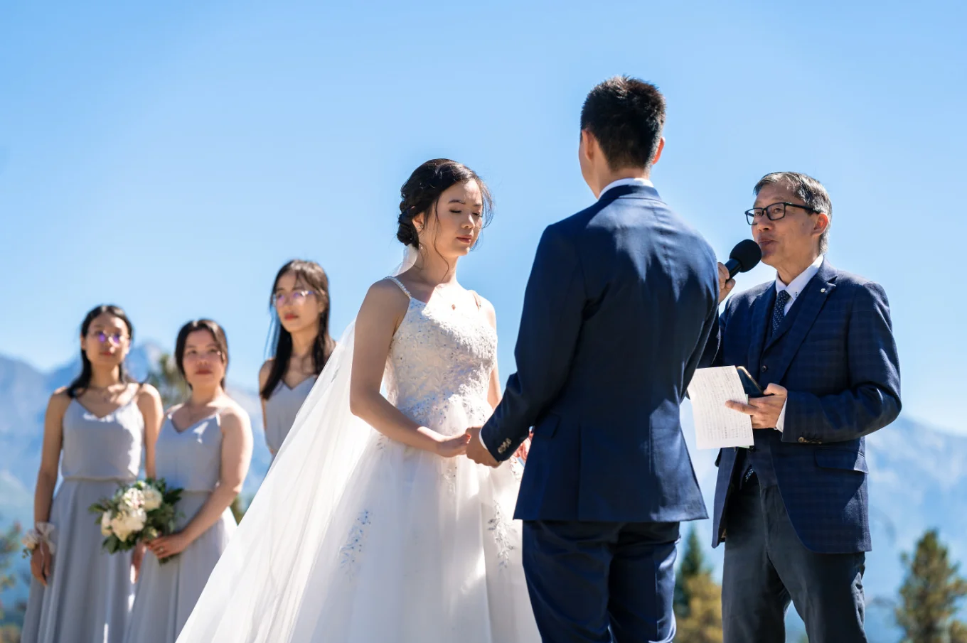 bride and groom hold their hands while banff officient giver them blessing.