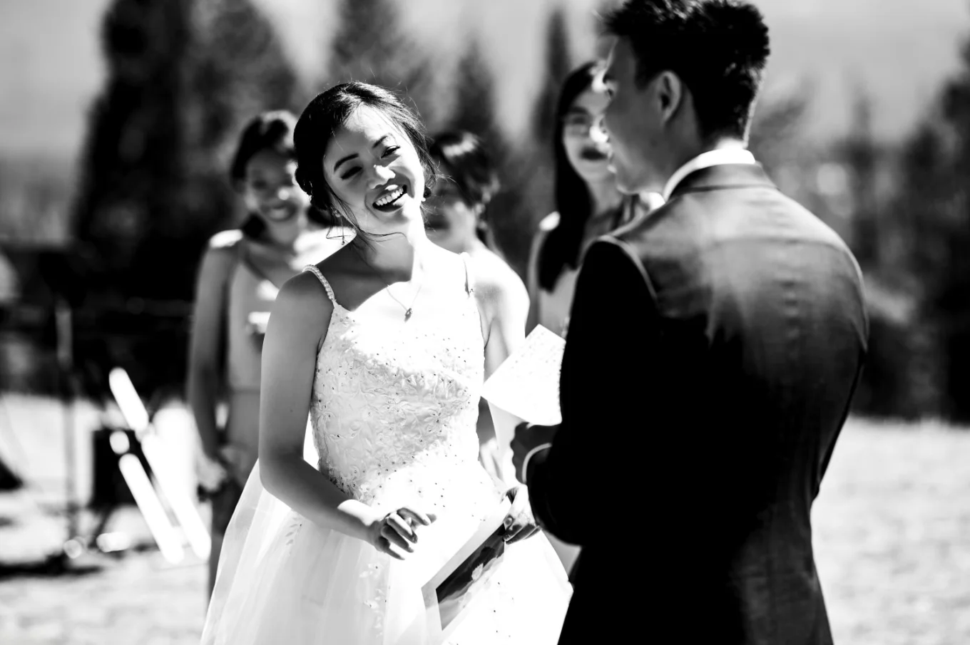 Bride smiles to the groom while he gives a speach during banff wedding ceremony.