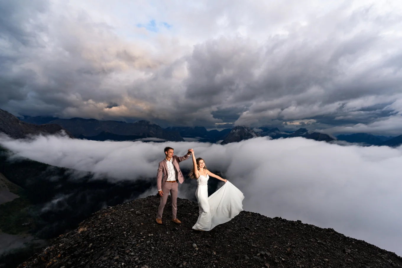 Newlyweds first dance at the top of the mountain during elopement. Moment captured by Banff Wedding Photographer in a cloudy day.