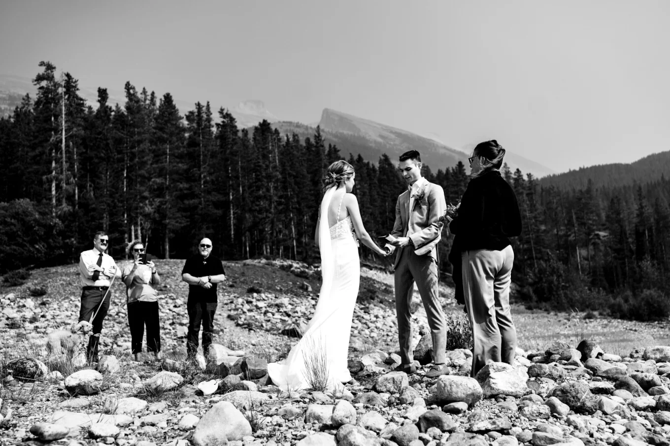 Elopement ceremony in Banff captured by Banff Wedding Photographer. Bride and groom hold their hands and family stand behind.