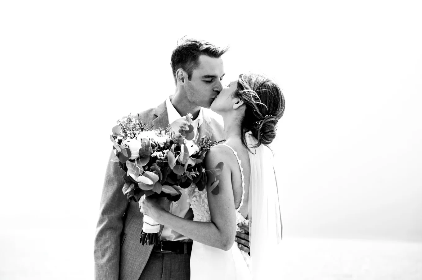 A newlywed couple shares a romantic kiss against the backdrop of the lake in Banff.