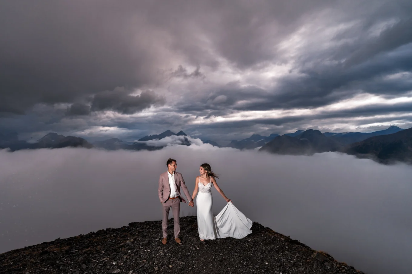 Wedding photography in Banff, showcasing the beauty of the Canadian Rockies and capturing precious moments of the bride and groom holding hands and looking into each others eyes.
