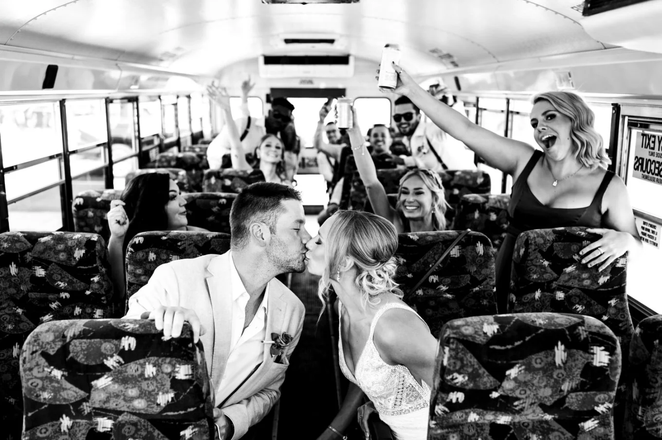 Bride and groom share a kiss in the bus.