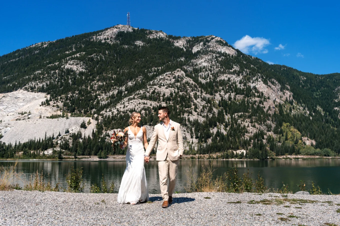Bride and groom walk and hold their hands in the mountains.