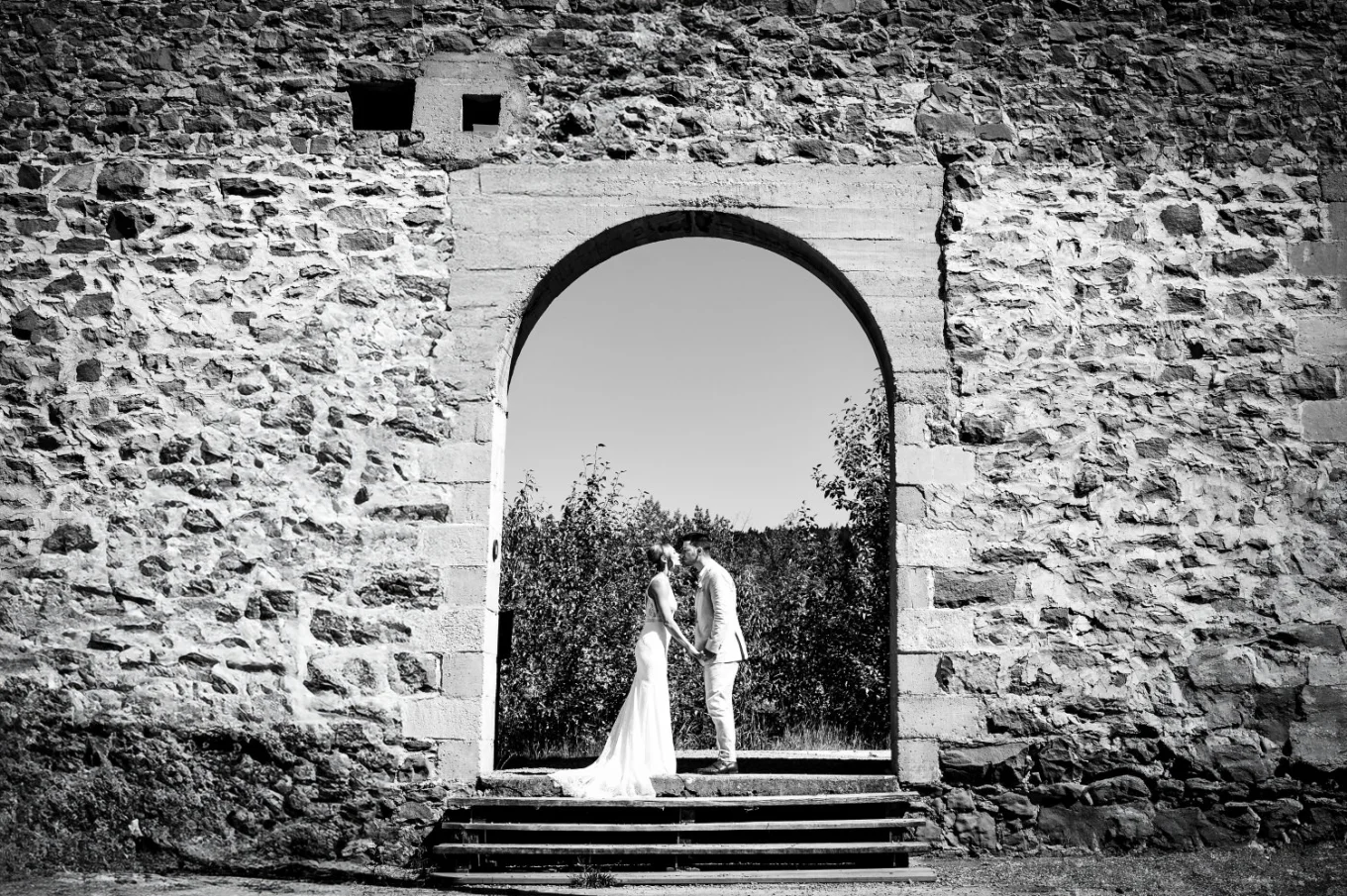 Bride and groom share a kiss in the ols, brick building.