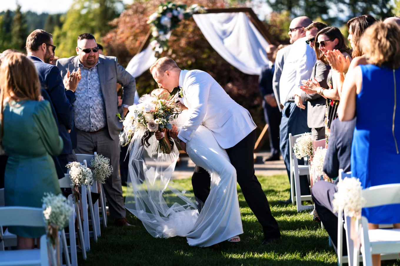Bride and groom share a kiss while walking back the aisle during Calgary Wedding