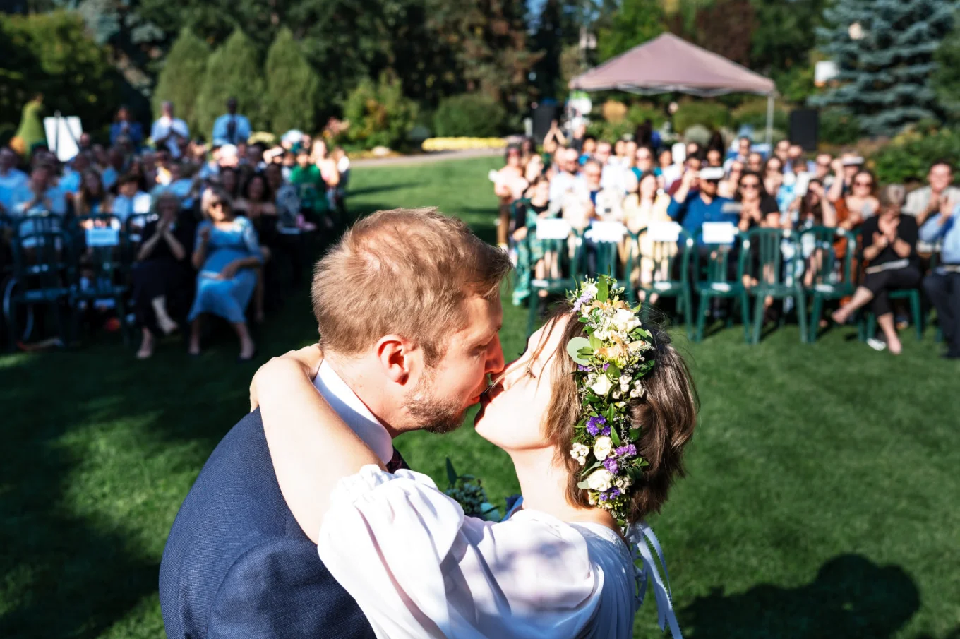 First kiss at the wedding in Calgary Zoo. Behind all the guests watching bride and groom.