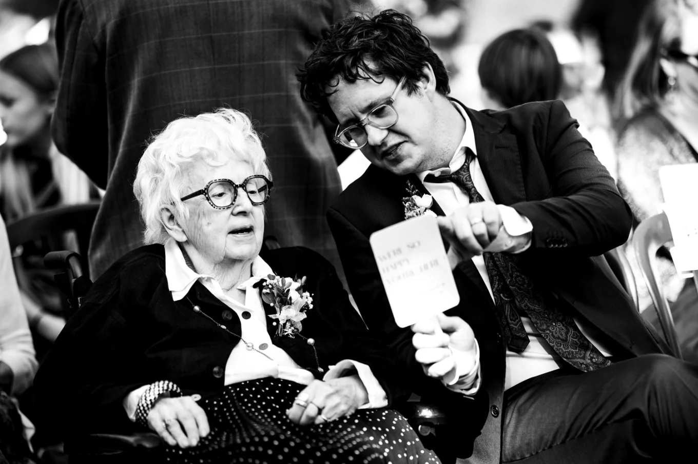 A man shows the grandmother the schedule of the Calgary Wedding