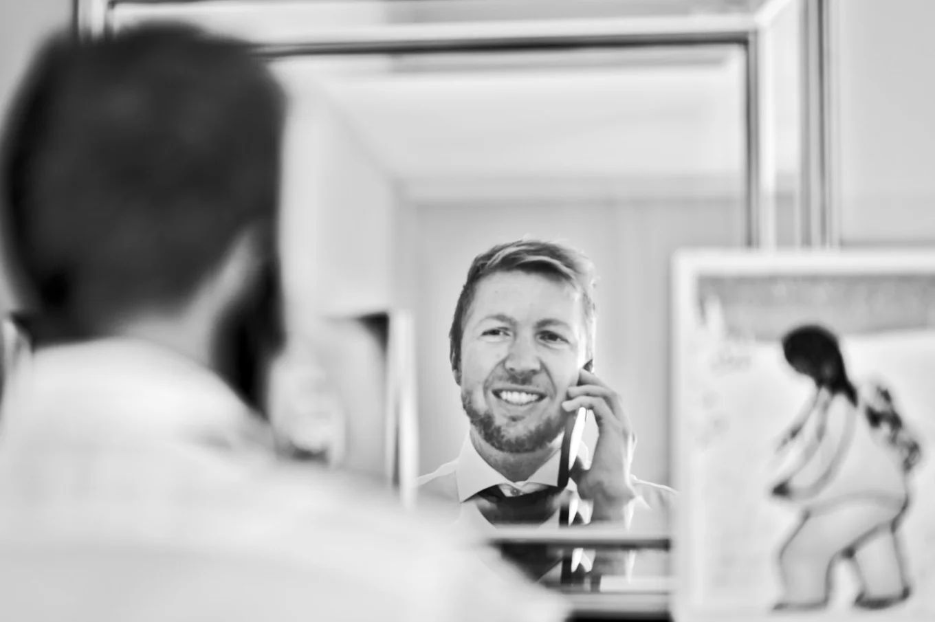 Groom looks at the mirror and talks with the bride before Calgary Wedding.
