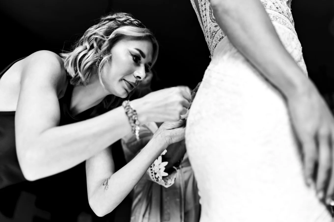 Sister of the bride zip the dress of the bride.