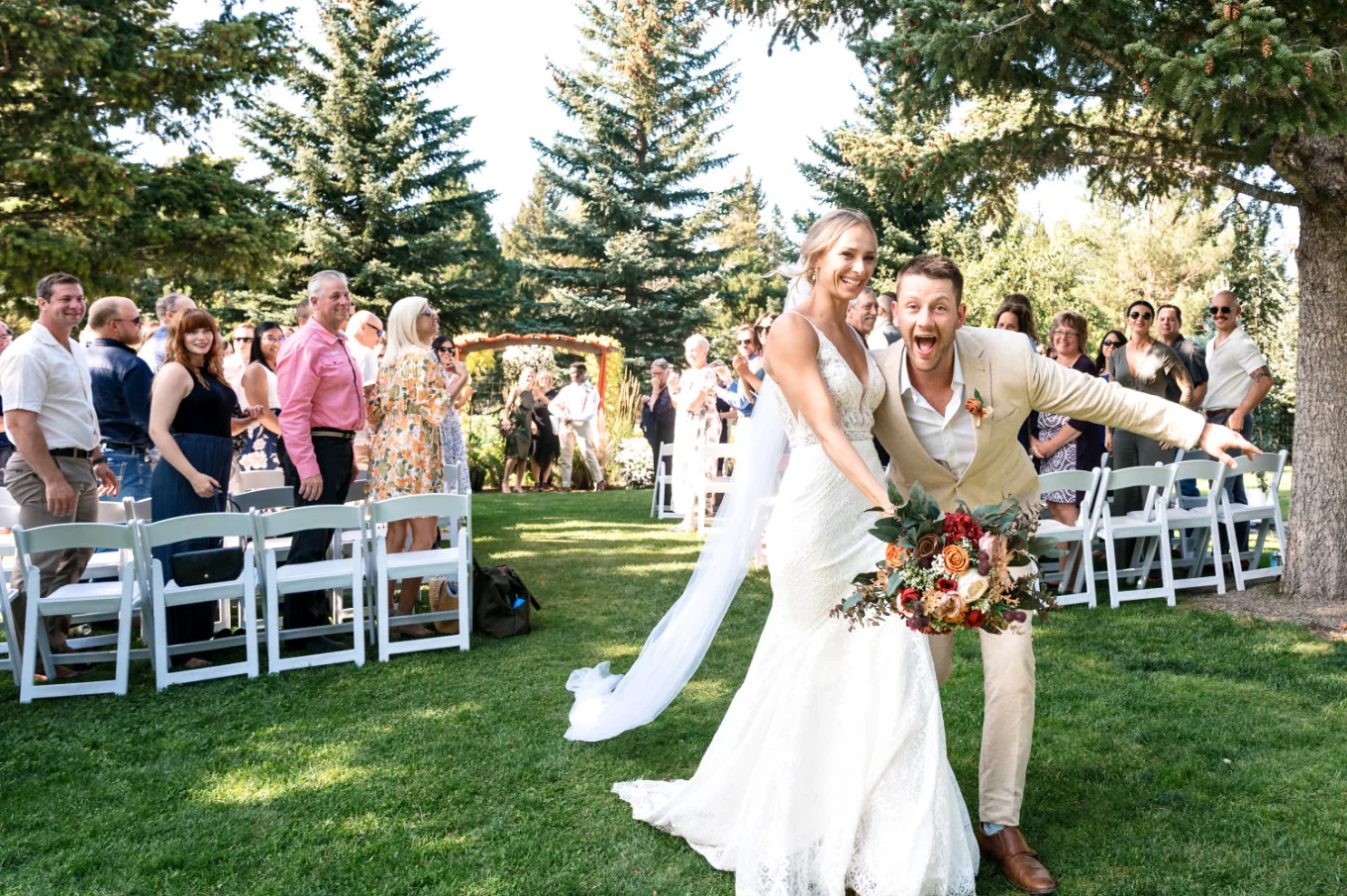 Bride and groom run down the aisle and scream into the camera. Quests are watching.