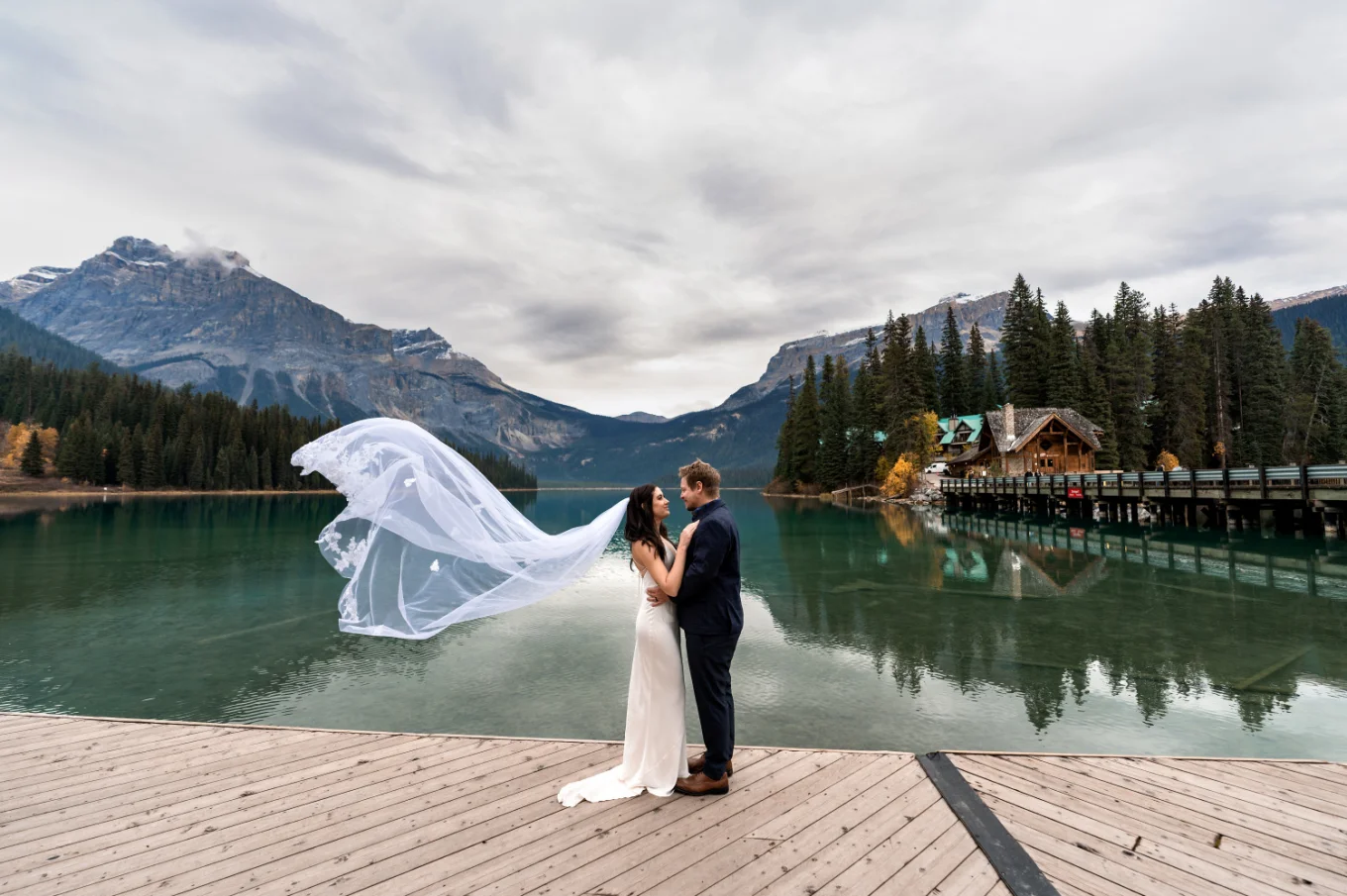 Bride and groom facing each other while the veil flying on the wind.